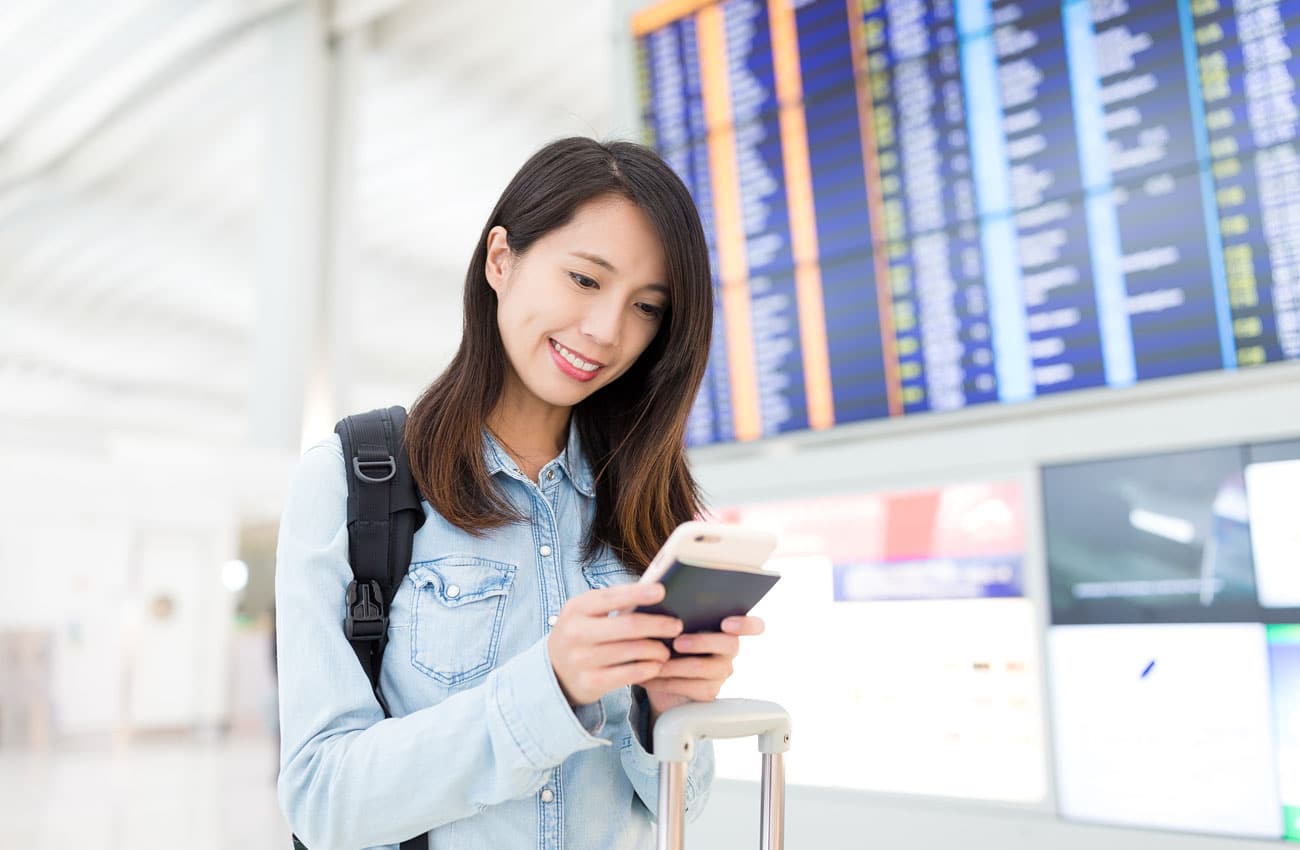 Frau am Flughafen mit mobilem Endgerät